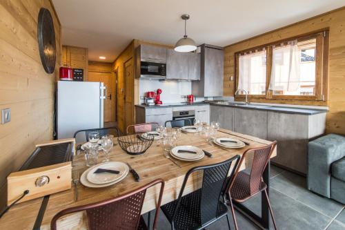 a dining room with a table and chairs and a kitchen at ODYSSEE B101 - Appartement traversant sur les pistes in La Toussuire