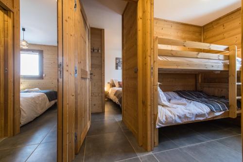two bunk beds in a room with wooden walls at ODYSSEE B101 - Appartement traversant sur les pistes in La Toussuire