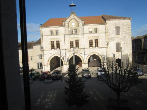 a large stone building with cars parked in a parking lot at Gîte La Bastide in Tournon-dʼAgenais