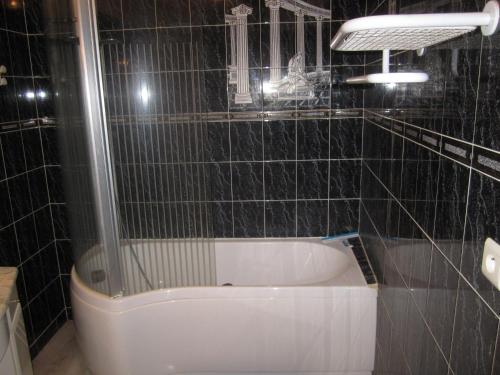 y baño de azulejos negros con bañera. en Gîte La Bastide, en Tournon-dʼAgenais