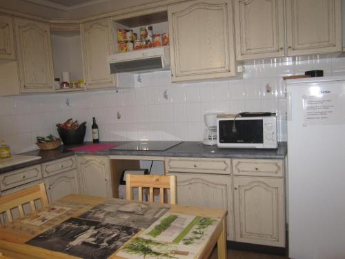 a kitchen with a table and a white refrigerator at Gîte La Bastide in Tournon-dʼAgenais