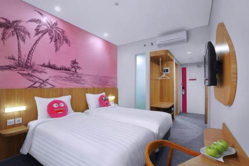 a bedroom with a large white bed with two pink pillows at favehotel Ketapang in Ketapang
