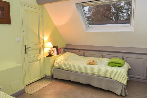 Un dormitorio con una cama con una almohada verde. en GITE LES ROCHES, en Moigny