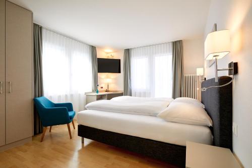 a hotel room with a bed and a blue chair at Hotel Schmid & Alfa in Brunnen