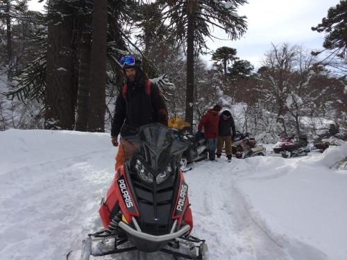 a man standing next to a snowmobile in the snow at Lodge Tikilen Caviahue in Caviahue