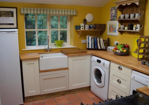 a kitchen with a washing machine and a washer at Bittles Cottage in Dorchester