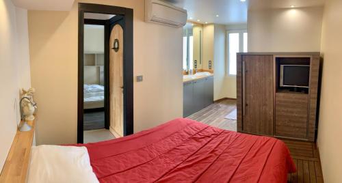 1 dormitorio con cama roja y TV en Appartement les pieds dans l'eau !, en Collioure