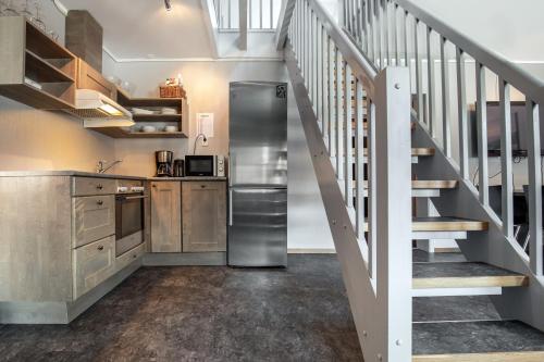 a kitchen with a stainless steel refrigerator next to a staircase at Hemsedal Cafe Skiers Lodge in Hemsedal