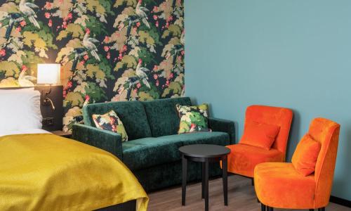a bedroom with a green couch and two orange chairs at Thon Hotel Bristol, Bergen in Bergen