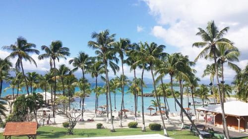uma vista para uma praia com palmeiras e para o oceano em Hotel Fleur d'Epee em Le Gosier