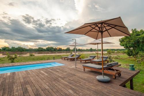 a patio with chairs and an umbrella and a pool at Chikunto Safari Lodge in Kakumbi
