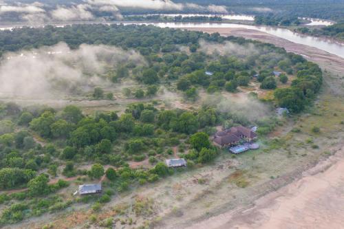 an aerial view of a house in a field next to a river at Chikunto Safari Lodge in Kakumbi