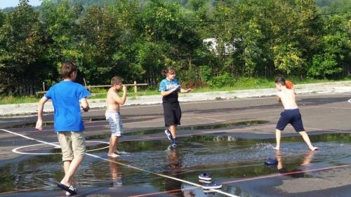 a group of young men playing in water on a road at Pensiunea ARC Bucovina in Vama