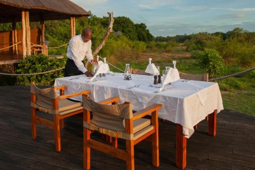 a man standing next to a table with a table cloth at Chikunto Safari Lodge in Kakumbi