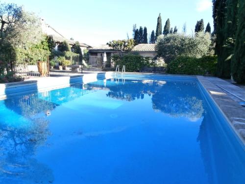 a swimming pool with blue water in a yard at Les grands pins in Saint-Andiol