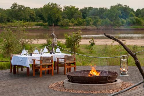 a table and a fire pit with a table and chairs at Chikunto Safari Lodge in Kakumbi