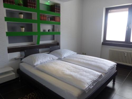 a bedroom with a bed with green shelves on the wall at Dasluki in Köngen