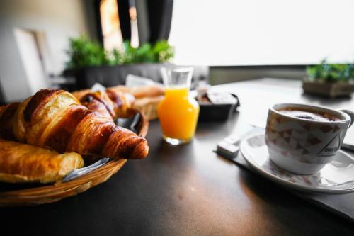 a table with a basket of croissants and a cup of coffee at Hostellerie LE PANEL in Mandelieu-La Napoule