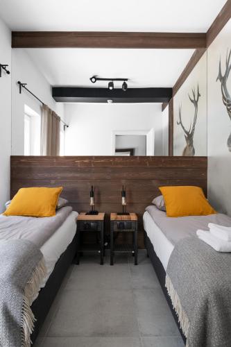 two beds in a room with two tables at Aparthotel Narciarska 2 in Korbielów