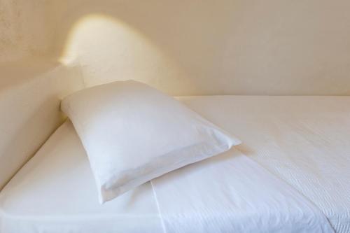 a white pillow sitting on top of a bed at Yialos Ios Hotel in Ios Chora