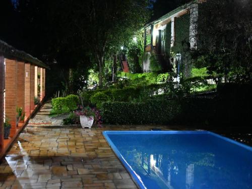 a swimming pool in front of a house at night at Hotel Bougainville in Penedo