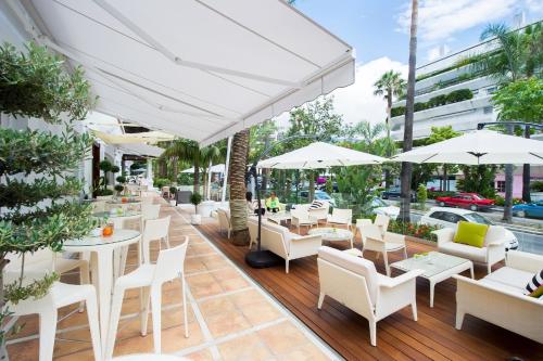 un restaurante con mesas blancas, sillas y sombrillas en Aparthotel Monarque Sultán, en Marbella