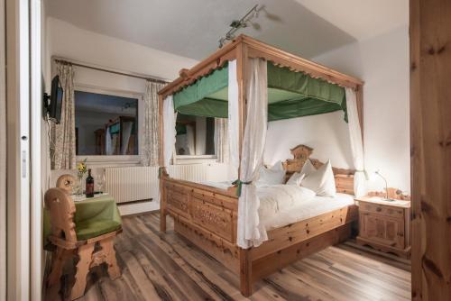ein Schlafzimmer mit einem Himmelbett und einem Schreibtisch in der Unterkunft Gasthof - Pension Ödsteinblick in Johnsbach