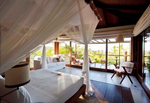 Txai Resort في إيتاكاري: غرفة نوم بسرير مظلة وغرفة معيشة