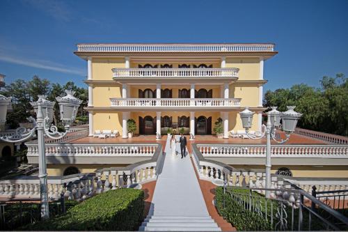 a large yellow house with a staircase leading up to it at Villa Le Zagare Relais & SPA in Gragnano