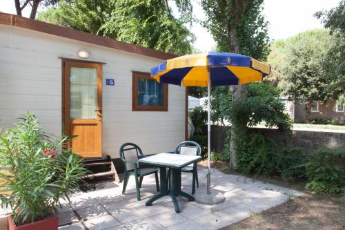 a table and chairs and an umbrella in front of a house at Camping Village Cavallino in Cavallino-Treporti