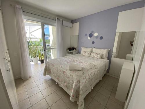Un dormitorio con una cama y una ventana grande. en Shiraz Jurere Florianópolis, en Florianópolis