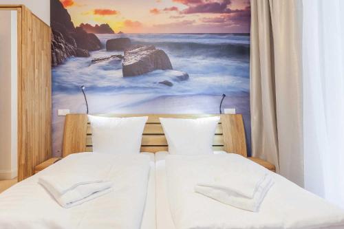 a bedroom with two beds with a painting on the wall at FIRST Wellentraum in Ostseebad Sellin