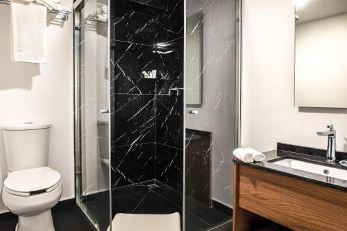 a bathroom with a toilet and a glass shower at Hotel Boutique Parque Centro in Mexico City