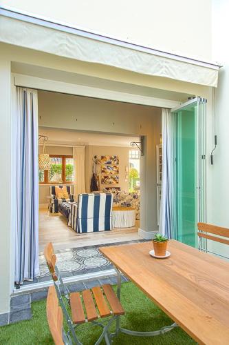 a patio with a wooden table and a living room at Charming Coastal Townhouse at The Majestic in Kalk Bay