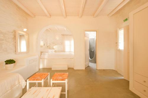 a white room with a bed and a bathroom at Yialos Ios Hotel in Ios Chora