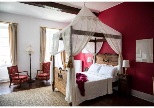 a bedroom with a canopy bed with red walls at La Résidence Chambre d'Hotes in Saint-Antonin