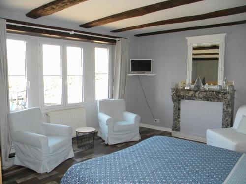 a bedroom with a bed and two chairs and a fireplace at Gîte et Chambres d'hôtes du Domaine du Val Bruant in Arc-en-Barrois