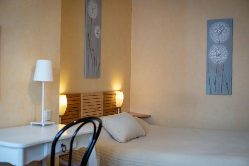 a bedroom with a bed and a desk with a lamp at HotelLe MaraisCaillebotte in Challans