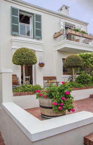 a white house with two potted plants and a balcony at Charming Coastal Townhouse at The Majestic in Kalk Bay