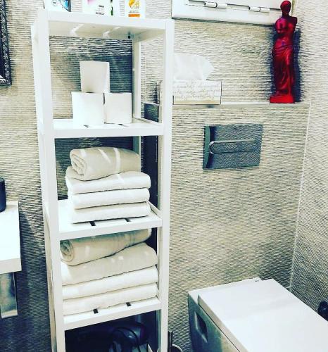 a bathroom with a white shelf with towels at Family Deluxe Apartment Beach in Castelldefels
