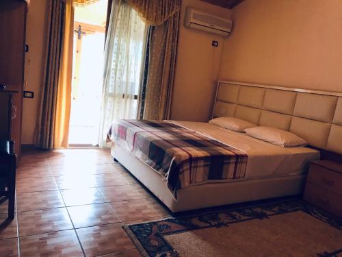 sypialnia z łóżkiem i dużym oknem w obiekcie Gold Guest House & Bar w mieście Përmet
