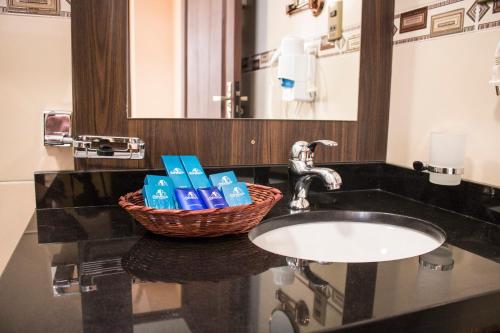 a bathroom sink with a basket of toiletries on it at Hotel Pairumani in Cochabamba