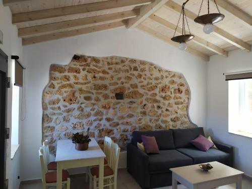 a living room with a couch and a stone wall at Oliveways in Liapades