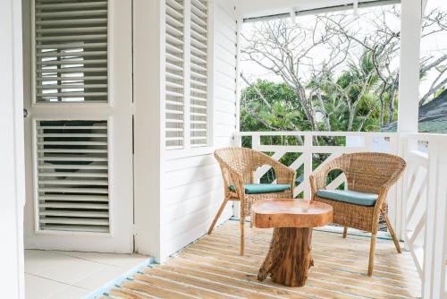 a porch with two chairs and a wooden table at El Mosquito Boutique Hotel Playa Bonita in Las Terrenas