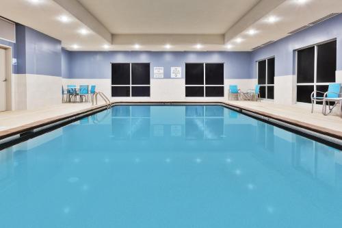 une grande piscine avec des murs bleus et des chaises bleues dans l'établissement Holiday Inn Express & Suites - Cartersville, an IHG Hotel, à Cartersville