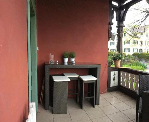 a table and stools on a patio with a wall at Villa Streintz in Millstatt