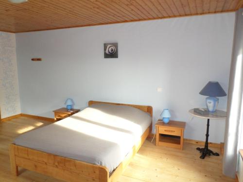ein Schlafzimmer mit einem Bett und einem Tisch mit einer Lampe in der Unterkunft Gite le Sauceley Maison de vacances pour 6 à 10 personnes in Girmont-Val-dʼAjol