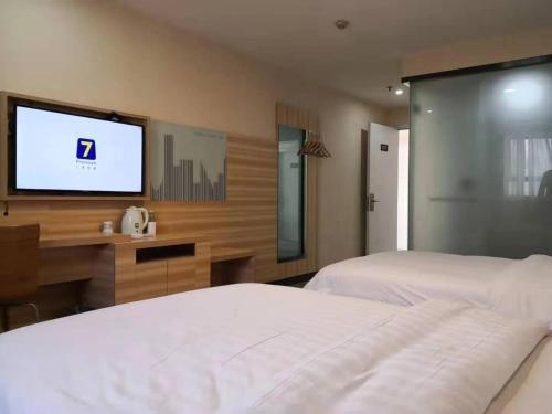 a bedroom with a bed and a flat screen tv at 7Days Inn Changsha Yinpenling ridge AUX Plaza in Changsha