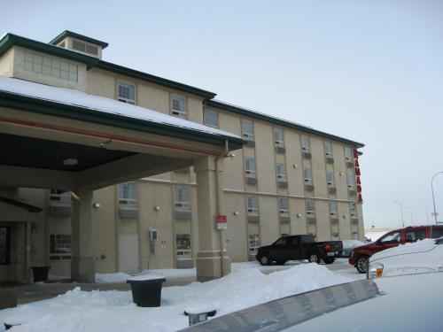 a snow covered parking lot in front of a building at Ramada by Wyndham Red Deer Hotel & Suites in Red Deer