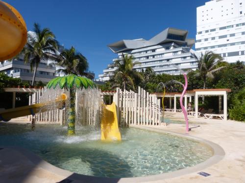 a water slide in a pool with buildings in the background at State of the Art Condos en la mejor Playa de Cancun frente a PLAZA LA ISLA in Cancún